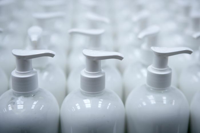 White plastic soap bottles in rows, cosmetics laboratory assembly line
